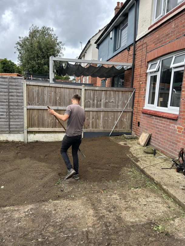 A member of the Green Growth team appplying top soil after a garden clearance.